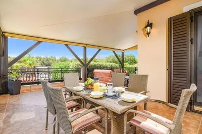 a dining room with a table and chairs on a balcony at Villa Alnika Azalea by Villa Plus in Lachania
