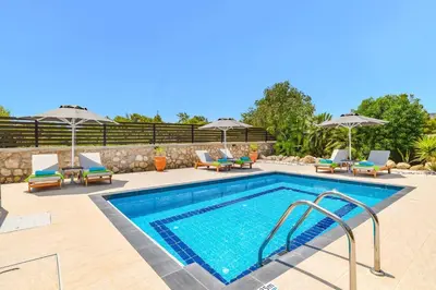 a swimming pool with chairs and umbrellas next to at Villa Alnika Azalea by Villa Plus in Lachania