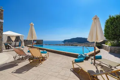 a group of chairs and umbrellas next to a swimming pool at Villa Anastasia Rodos by Villa Plus in Líndos