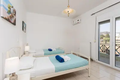 a bedroom with two beds and a balcony at Amphitrite Villa in Gennadi