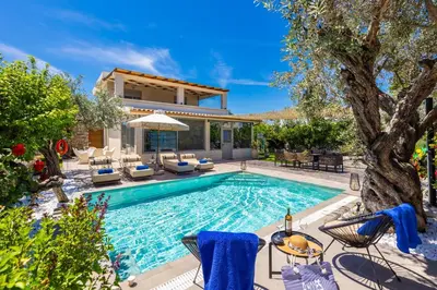 a swimming pool with chairs and a house at Villa Ammos in Afantou