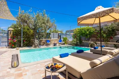 a swimming pool with a couch and an umbrella at Villa Ammos in Afantou