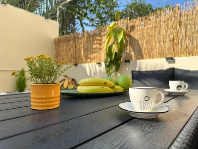 a wooden table with a cup of coffee and fruit on it at Seaside Deluxe Apartment in Ialyssos