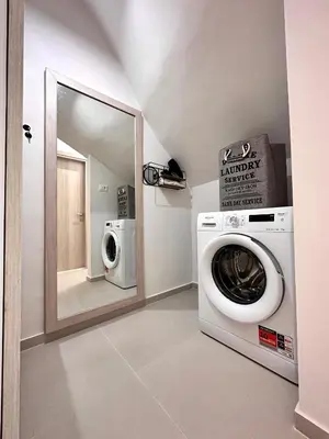 a laundry room with a washing machine and a mirror at Seaside Deluxe Apartment in Ialyssos