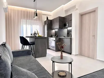 a living room with a couch and a kitchen at Seaside Deluxe Apartment in Ialyssos