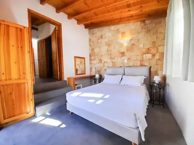a bedroom with a white bed and a brick wall at St. George Studios in Rhodes Town