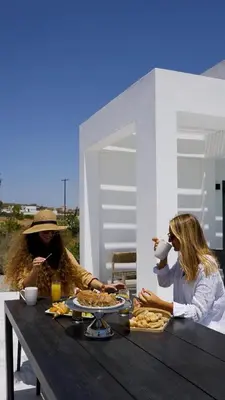 two women sitting at a table eating food at Seafish Villa, 2 Luxury Villas at Lachania Beach in Lachania