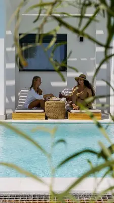 three women sitting on a bench next to a pool at Seafish Villa, 2 Luxury Villas at Lachania Beach in Lachania