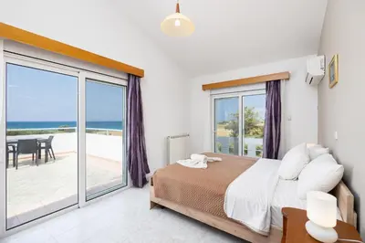 a bedroom with a bed and a balcony with the ocean at Villa Sunset Paradise in Kalavárda