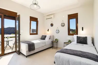 a bedroom with two beds and a table at Villa Angelika Lindos by Villa Plus in Pefki Rhodes