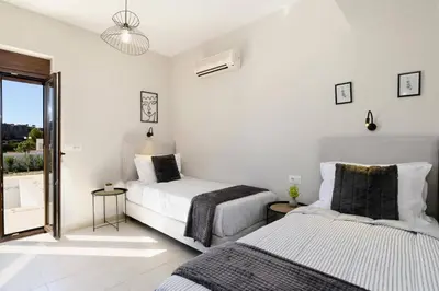 two beds in a white room with a window at Villa Angelika Lindos by Villa Plus in Pefki Rhodes