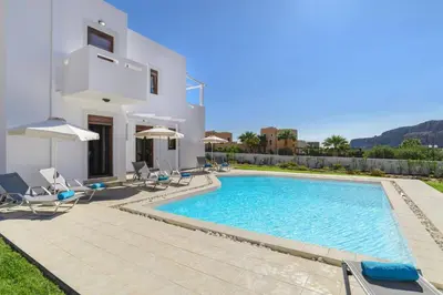 a villa with a swimming pool in front of a house at Villa Angelika Lindos by Villa Plus in Pefki Rhodes