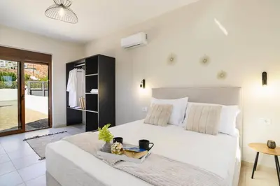 a bedroom with a large white bed and a table at Villa Angelika Lindos by Villa Plus in Pefki Rhodes