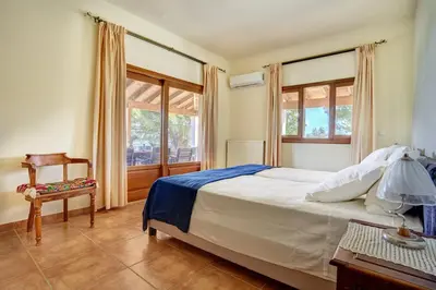 a bedroom with a bed and a chair and a window at Villa Eremia in Pastida