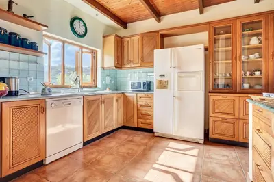 a kitchen with a white refrigerator and wooden cabinets at Villa Eremia in Pastida