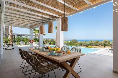 an outdoor dining room with a wooden table and chairs at Sunset Hill Villa Rhodes in Gennadi