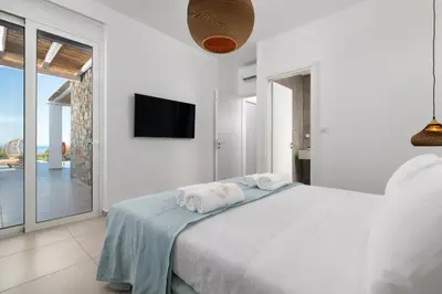 a white bedroom with a bed and a flat screen tv at Sunset Hill Villa Rhodes in Gennadi