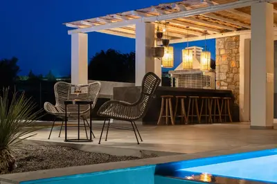 two chairs and a bar on a patio at night at Sunset Hill Villa Rhodes in Gennadi