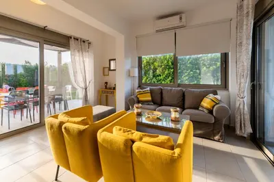 a living room with yellow chairs and a couch at Filoxenia Villas in Gennadi