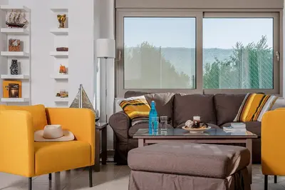 a living room with a couch and a table and yellow chairs at Filoxenia Villas in Gennadi
