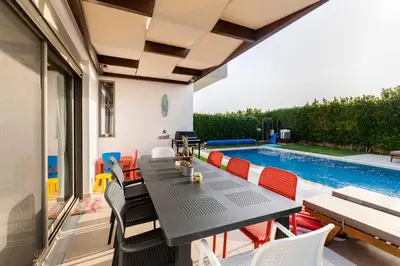 a patio with a table and chairs and a swimming pool at Filoxenia Villas in Gennadi
