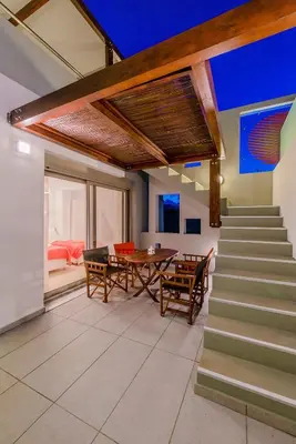 a living room with a table and chairs and stairs at Filoxenia Villas in Gennadi