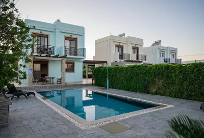 a villa with a swimming pool in front of a building at Petra Villas in Gennadi