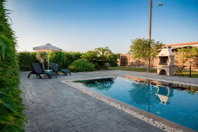 a swimming pool in a yard with two chairs next to it at Petra Villas in Gennadi