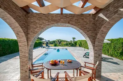 a patio with a table and chairs next to a swimming pool at Petra Villas in Gennadi