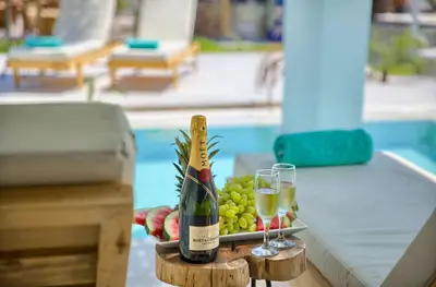 a bottle of wine and glasses on a table next to a pool at Alia Suites and Spa in Haraki