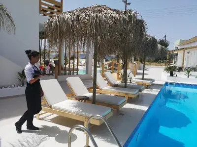 a woman is standing next to a swimming pool at Alia Suites and Spa in Haraki