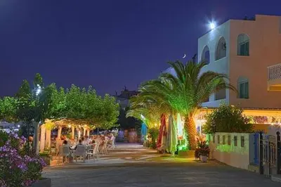 a group of people sitting outside of a building at night at Samanthas LUXURY APARTMENT in Haraki