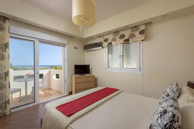 a bedroom with a bed and a window with a balcony at Evergreen Seaside Villa with private pool in Faliraki