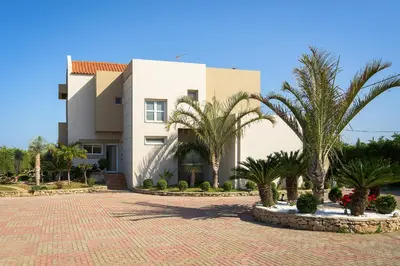 a building with palm trees in front of it at Evergreen Seaside Villa with private pool in Faliraki