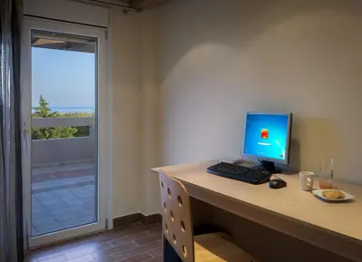 a desk with a computer monitor and a keyboard and mouse at Evergreen Seaside Villa with private pool in Faliraki