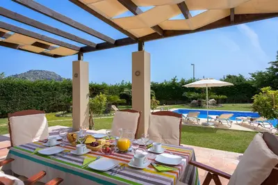 a table with food on it with a view of a pool at Evergreen Seaside Villa with private pool in Faliraki