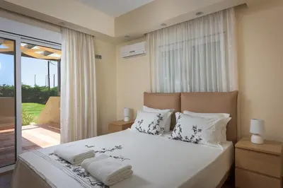 a bedroom with a bed with white sheets and pillows at Evergreen Seaside Villa with private pool in Faliraki