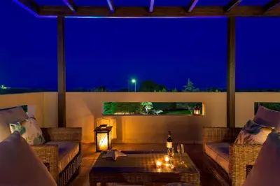 a patio with couches and a table at night at Evergreen Seaside Villa with private pool in Faliraki