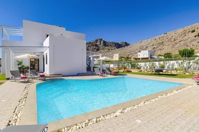 a villa with a swimming pool in front of a house at Villa Pandora Lindos by Villa Plus in Líndos