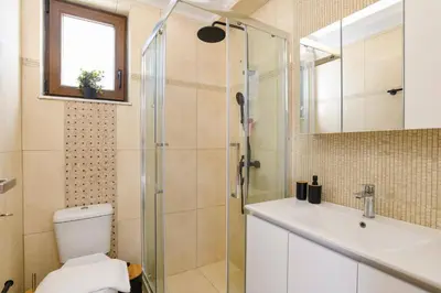 a bathroom with a shower and a toilet and a sink at Villa Pandora Lindos by Villa Plus in Líndos