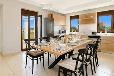 a kitchen with a wooden table and chairs at Villa Pandora Lindos by Villa Plus in Líndos