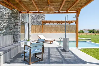 a patio with a table and benches next to a pool at Haraki Luxury Villas in Haraki