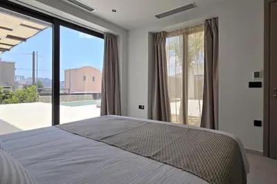 a bedroom with a large bed and a large window at Trapezia Luxury Living in Kolimbia