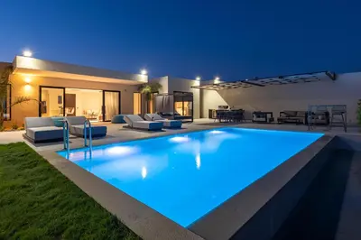 a swimming pool in front of a house at night at Trapezia Luxury Living in Kolimbia