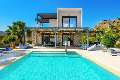 a villa with a swimming pool in front of a house at Villa Apollon Lindian Palm by Villa Plus in Kiotari