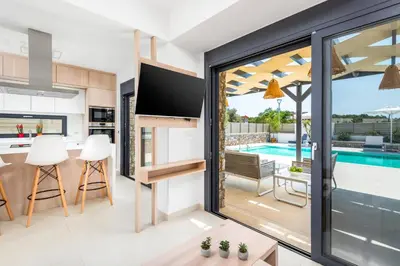 a kitchen and living room with a view of a swimming pool at Villa Apollon Lindian Palm by Villa Plus in Kiotari