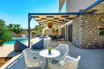a patio with a table and chairs and a pool at Villa Apollon Lindian Palm by Villa Plus in Kiotari