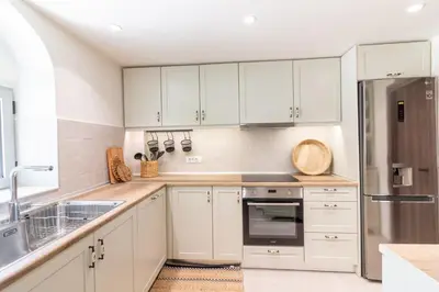 a kitchen with white cabinets and a stainless steel refrigerator at Mounouria House Koskinou in Koskinou