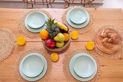 a wooden table with plates and a bowl of fruit at Mounouria House Koskinou in Koskinou