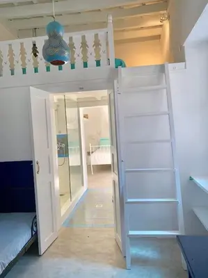 a room with a bunk bed with a ladder at seasalthouse - famous tv location in Koskinou